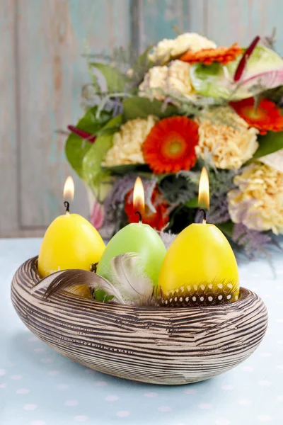 Easter candles in ceramic bowl decorated with quail feathers — Stock Photo, Image