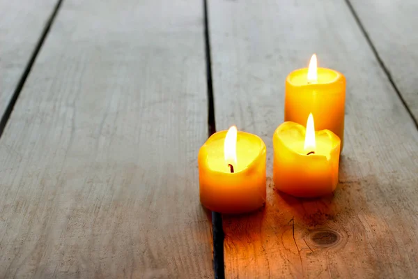 Simple golden candles on wooden table — Stock Photo, Image