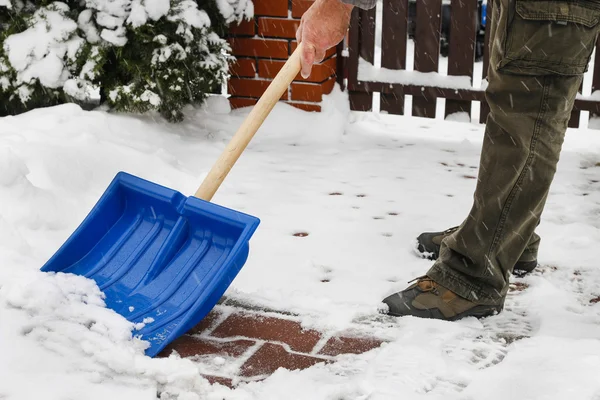 Человек убирает снег с тротуара после метели — стоковое фото
