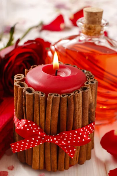 Red scented candle decorated with cinnamon sticks. Rose petals — Stock Photo, Image