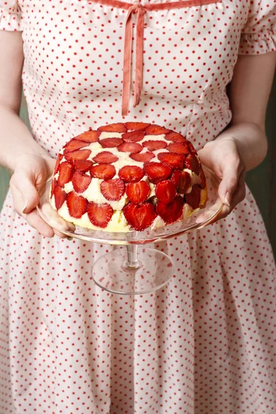 Woman holding strawberry cake on cake stand — Stockfoto