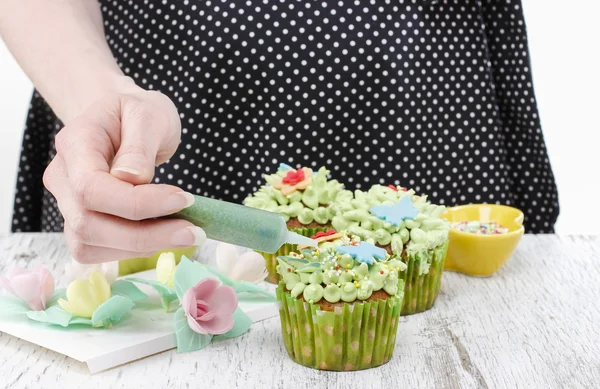 Woman decorates easter cupcakes — Stock Photo, Image