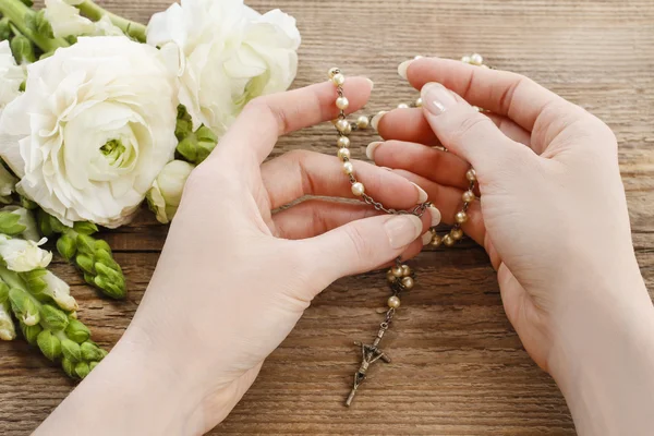 Woman holding wooden rosary in hands. — Stock Photo, Image