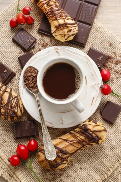 Xícara de café, barra de chocolate e eclairs — Fotografia de Stock