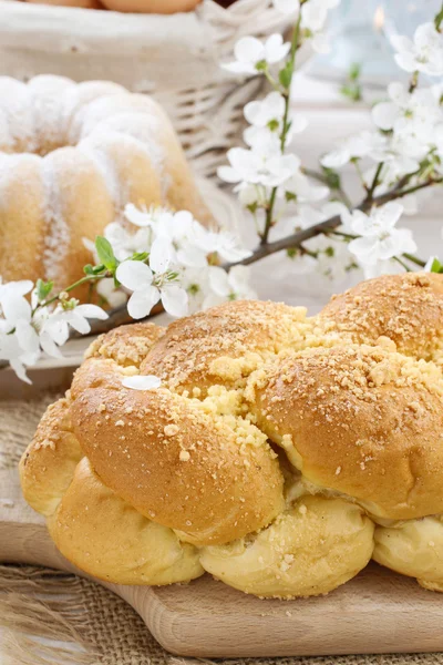 Loaf of sweet bread and cherry blossom twig in the back — Stock Photo, Image