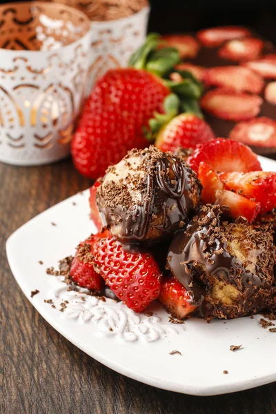 Profiteroles with strawberries and chocolate sauce — Stock Photo, Image