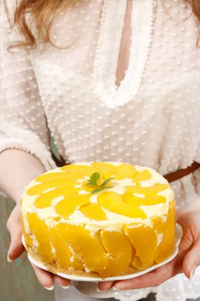 Woman holding peach cheese cake — Stock Photo, Image