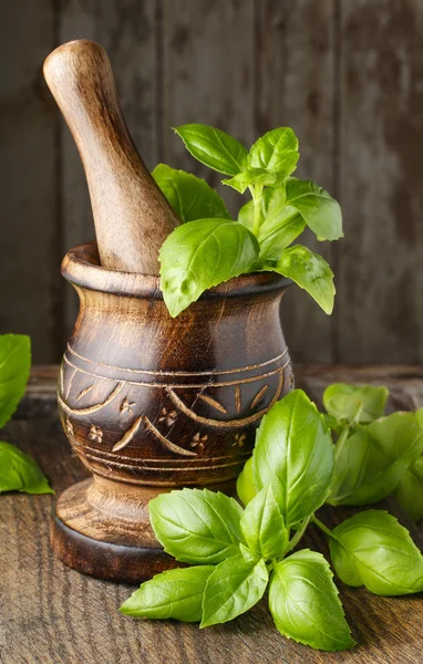 Mortier en bois et feuilles de basilic sur la table — Photo