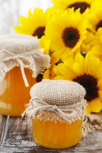 Potten van honing en mooie zonnebloemen — Stockfoto