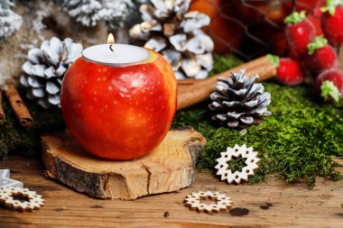 Kadın, elma, mum ve köknar dallarıyla nasıl Noel süsü yapılacağını gösteriyor. Adım adım, öğretici.