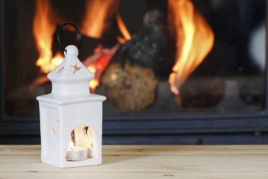 İçinde mum olan seramik fener. Arka planda şömine. Parti zamanı