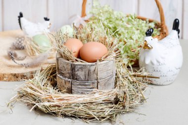 Seramik tavuk heykelcikleri, yumurtalar ve yeşil çiçeklerle şirin Paskalya süsleri. Kutlama zamanı.