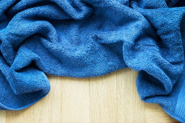 Mavi kumaştan yapılmış yumuşak havlu ahşap arka planda yatıyor. Grafiksel kaynaklar