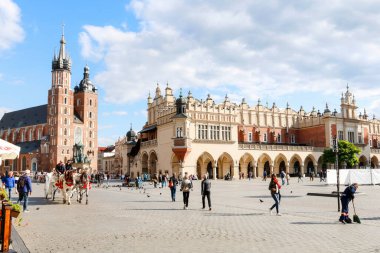 KRAKOW, POLAND - 17 Mayıs 2024: Sukiennice ve Mariacki Kilisesi Krakow, Polonya 'daki Ana Pazar Meydanı' nda (Rynek). Turistler için tatil yeri