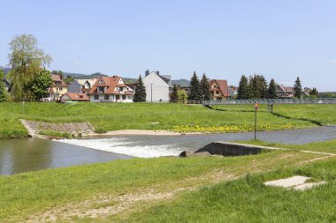 NOWY TARG, POLAND - 27 Mayıs 2023: Nowy Targ 'daki Dunajec Nehri Bulvarı. Deniz kıyısındaki tek aile evlerinin büyüleyici mülkleri. Turistler için tatil yeri