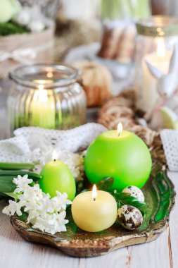 Mumlar, buxular, sümbül çiçekleri ve bıldırcın yumurtalarıyla Paskalya sofrası süslemesi. Şenlikli parti dekorasyonu