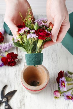 Çiçekçi iş başında. Kırmızı carnat ile çiçek düzenleme yapmaya kadın