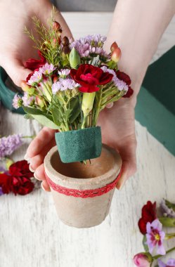 Çiçekçi iş başında. Kırmızı carnat ile çiçek düzenleme yapmaya kadın