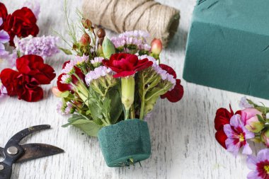 Çiçekçi iş başında. Kırmızı carnat ile çiçek düzenleme yapmaya kadın