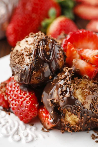 Profiteroles with strawberries and chocolate sauce — Stock Photo, Image
