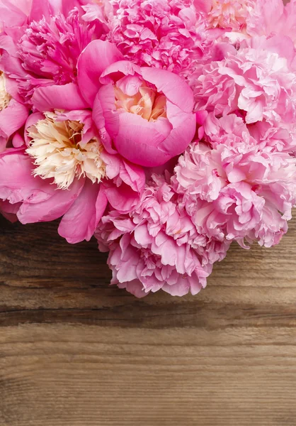 Prachtige roze pioenrozen op bruin rustiek houten achtergrond. — Stockfoto