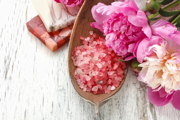 Red sea salt and peonies on wooden table — Stock Photo, Image