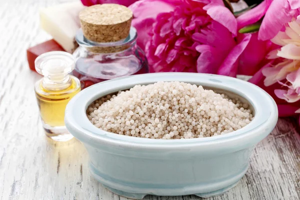 Cuenco de sal marina, aceites esenciales, barras de jabón y flores de peonía — Foto de Stock