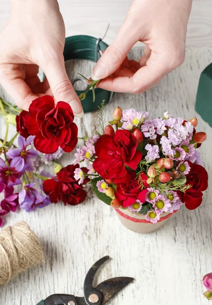 Florista no trabalho. Mulher fazendo arranjo floral com carnat vermelho — Fotografia de Stock