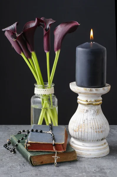 Black candle and bouquet of black calla flowers (Zantedeschia). — Stock Photo, Image
