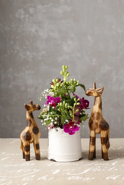 Arranjo floral com orquídeas violetas e figuras de madeira de gir — Fotografia de Stock