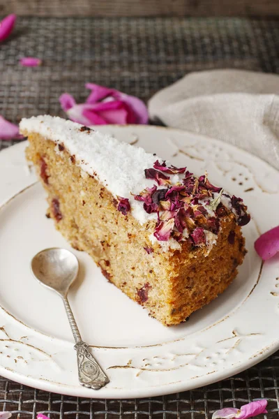 Carrot vegan cake with coconut icing and dried wild rose petals — Stock Photo, Image