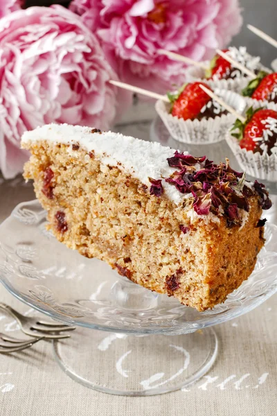 Carrot vegan cake with coconut icing and dried wild rose petals — Stock Photo, Image