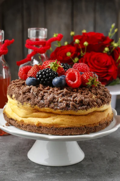 Cheesecake with chocolate topping decorated with summer fruits — Stock Photo, Image