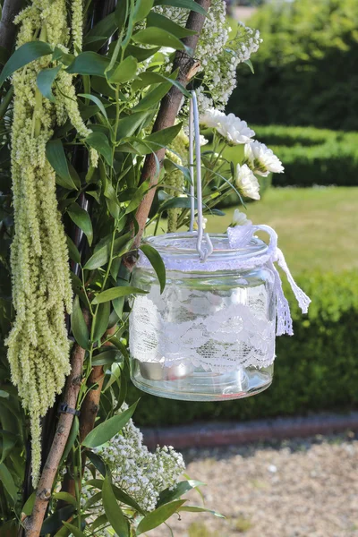 Lanterne en verre décorée de dentelle blanche suspendue à l'arc de mariage — Photo
