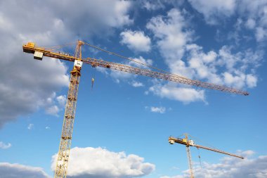 NOWY TARG, POLAND - Nisan 04, 2025: Mavi gökyüzünün arka planında görünen inşaat vinçleri. Grafiksel kaynaklar