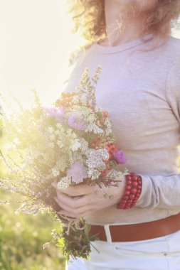 Modern elbiseli genç kadınlar çayırlardan büyük bir buket yaban çiçeği tutuyorlar. Parti dekoru