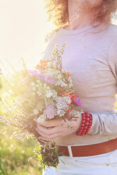 Modern elbiseli genç kadınlar çayırlardan büyük bir buket yaban çiçeği tutuyorlar. Parti dekoru