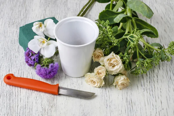 Frau arrangiert Blumenschmuck mit Rosen und weißen Orchideen — Stockfoto