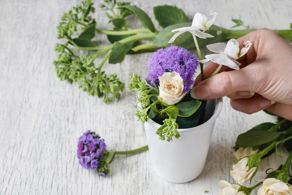 Mulher organizando decorações florais com rosas e orquídeas brancas — Fotografia de Stock