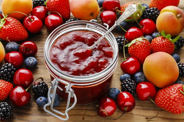 Jar of strawberry jams among summer and autumn fruits — Stock Photo, Image