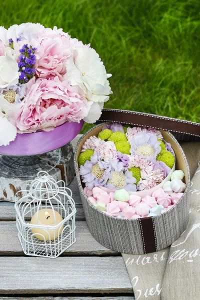 Gartenparty-Tisch: Schachtel mit Süßigkeiten und Blumenstrauß — Stockfoto
