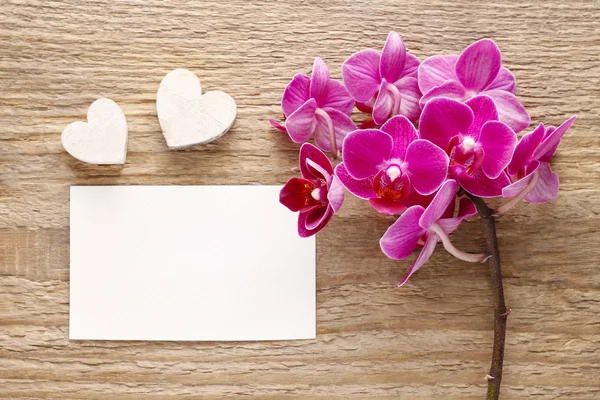 Bellissimi fiori di orchidea rosa e foglio di carta su legno — Foto Stock