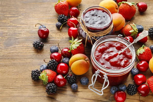 Jar of strawberry jams among summer and autumn fruits — Stock Photo, Image