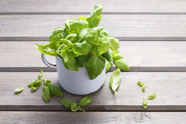 Pot of basil leaves on gray wooden background — 스톡 사진