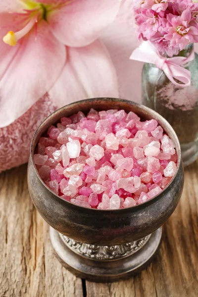 Bowl of pink sea salt and lily flower in the background — Stock Photo, Image