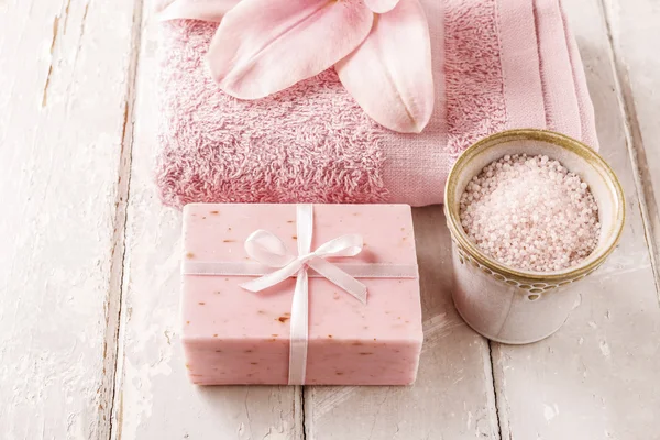 Bar de sabão, tigela de sal marinho, toalha rosa e flor de lírio — Fotografia de Stock
