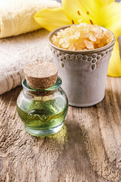 Botella de aceite esencial y flor de lirio amarillo en el fondo — Foto de Stock