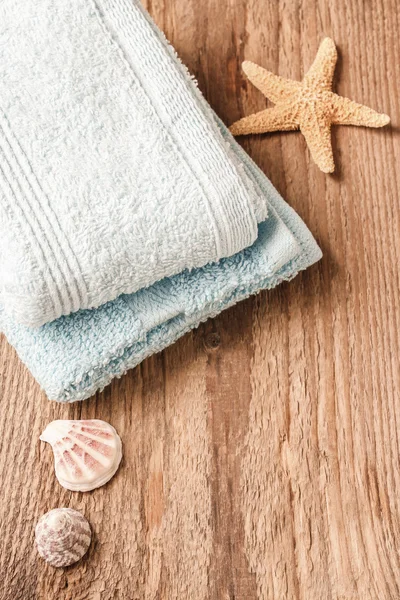 Towels, shells and a starfish on wooden table — Stock Photo, Image