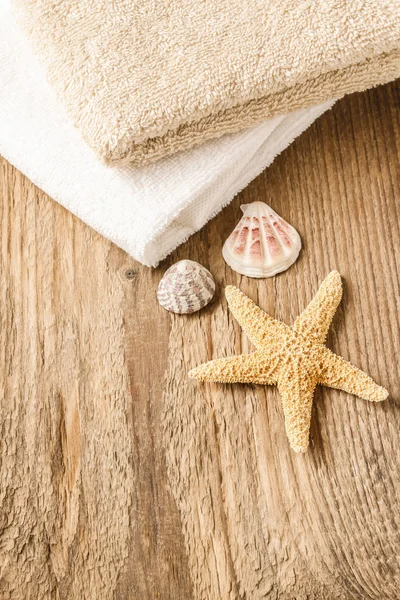 Towels, shells and a starfish on wooden table — Stock Photo, Image