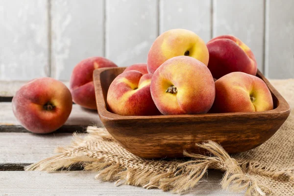 Skål med persikor på rustika träbord — Stockfoto